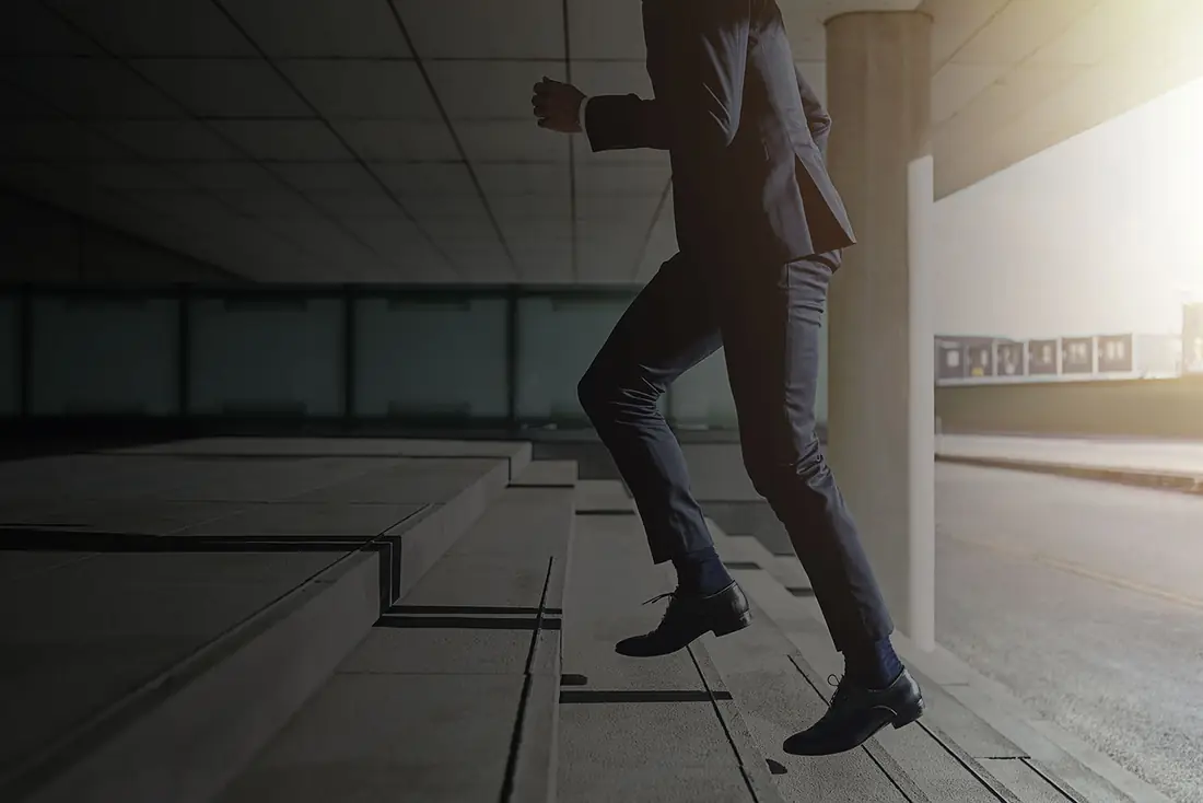 A man in a suit taking a flight of concrete stairs at a run.