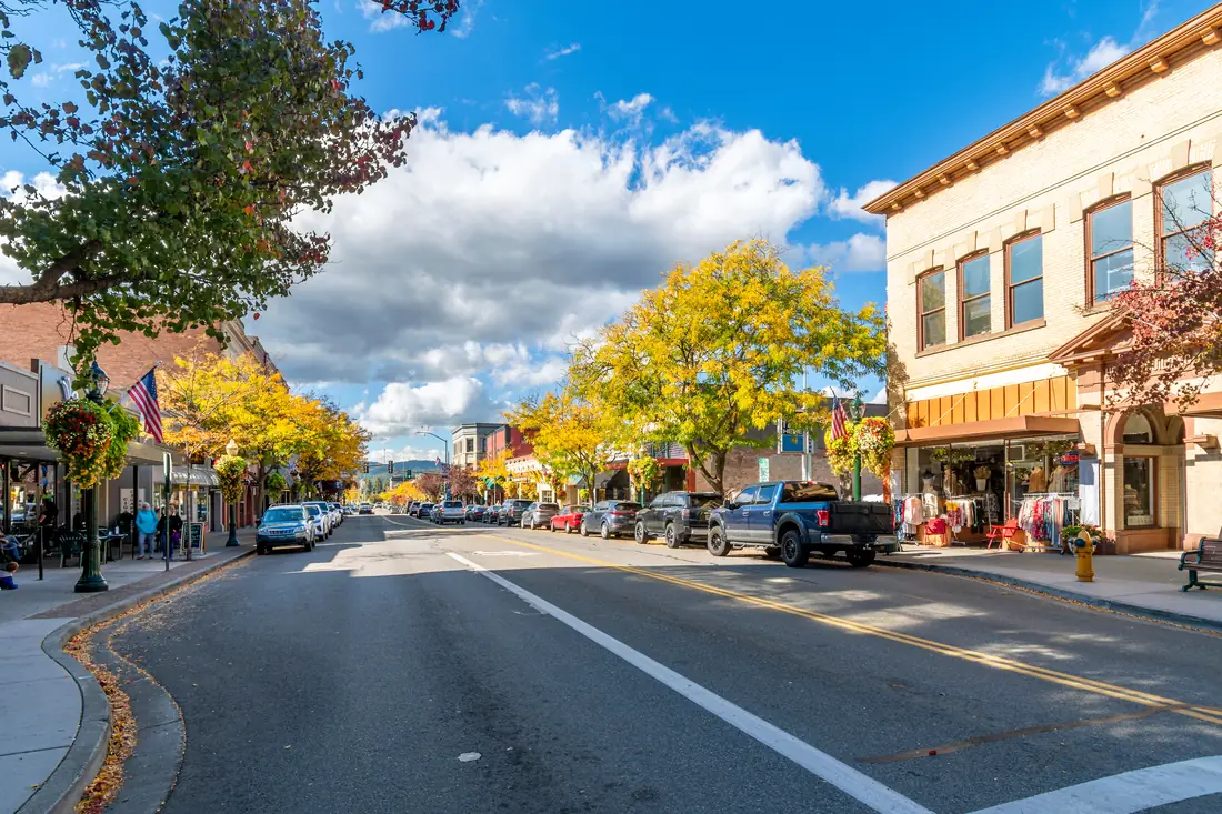A main street of independent shops and parked cars under a clear autumn sky.