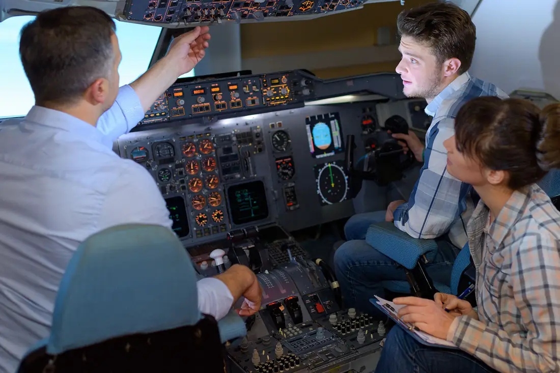 An instructor going through a flight simulator's controls with two trainees.